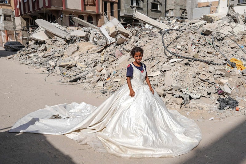 A Gazan girl wears a wedding dress found in the rubble of buildings destroyed by Israeli bombs, in Khan Younis. AFP