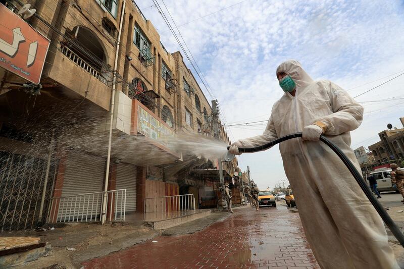 An Iraqi soldier wearing a protective suit sprays disinfectant to sanitise a street, during a curfew in Baghdad, Iraq. Reuters