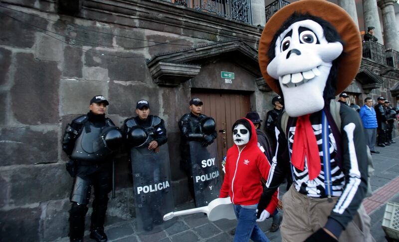A father and son wearing Coco movie character Halloween costumes walk past the government palace in Quito, Ecuador. AP Photo