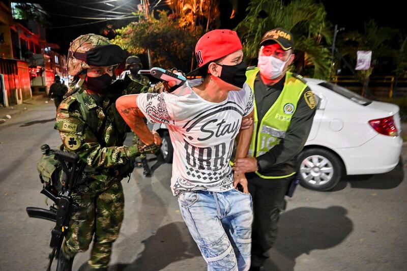 A man is detained in a control operation during a curfew imposed in red-zone neighbourhoods due to high numbers of Covid-19 cases in Cali, Colombia.  AFP