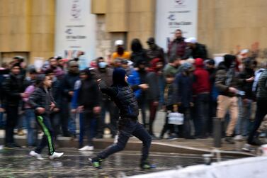 Anti-government protesters hurl stones at riot police behind a barrier during a rally outside of the Lebanese parliament in Beirut. EPA