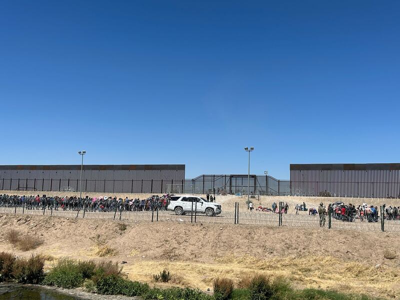 Hundreds of migrants queue at a gate along the US-Mexico border, hoping to claim asylum