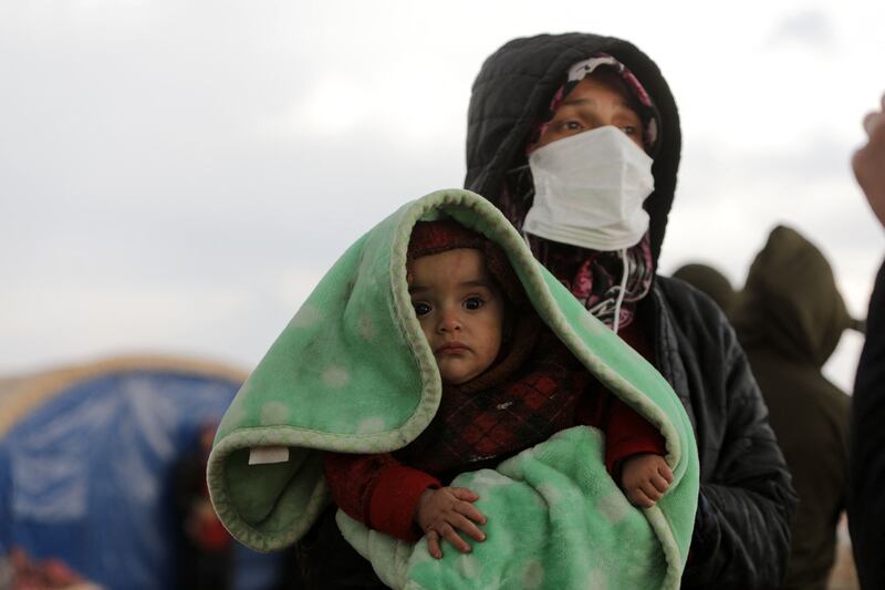 A woman carrying a baby watches search-and-rescue operations, four days after the deadly earthquake, in Jindayris. AFP