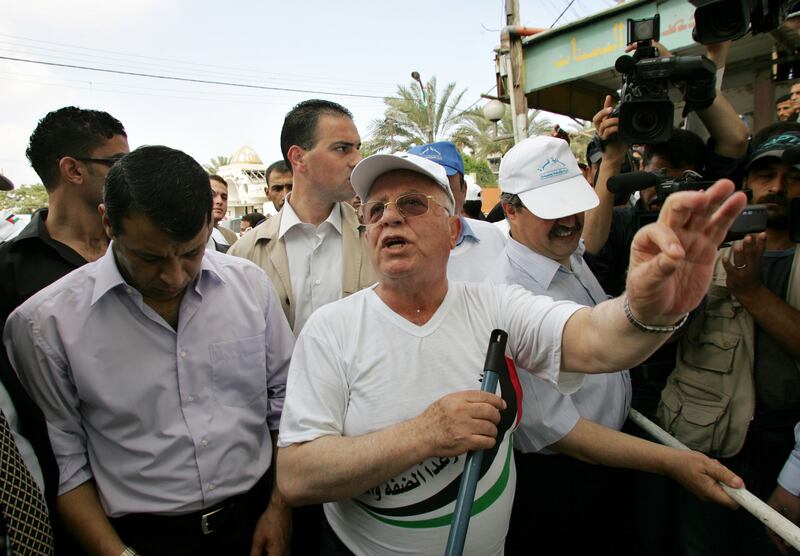 Prime minister Qurei talks to reporters while painting a wall in Gaza in August 2005. Reuters