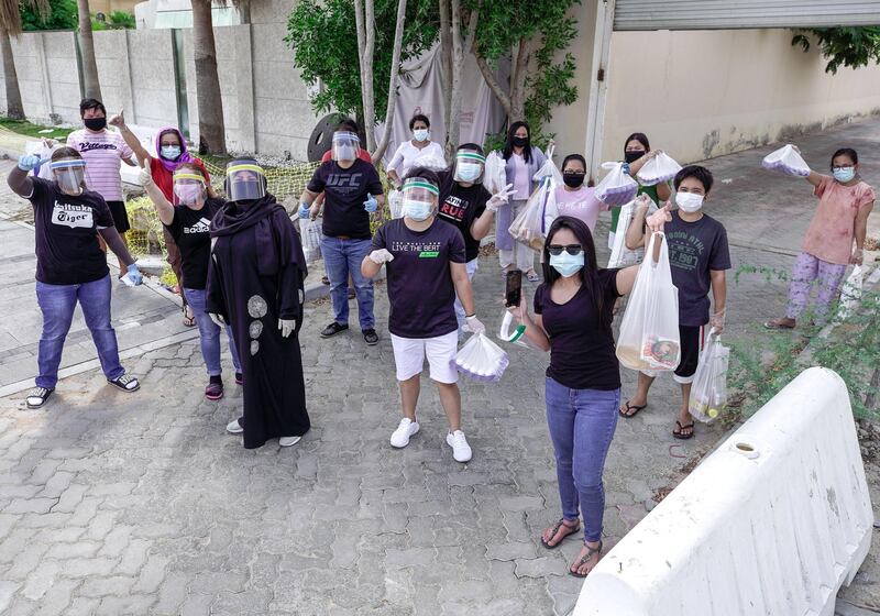 Abu Dhabi, United Arab Emirates, May 1, 2020.   
 Filipino laid off workers smile underneath their face masks after receiving some, rice, eggs, cooking oil and other daily essentials from Mona Mohamed Baraguir, a Flipino-Emirati citizen, at Khalifa City A, Abu Dhabi.
Victor Besa / The National
Section:  NA
Reporter:  Shireena Al Nuwais