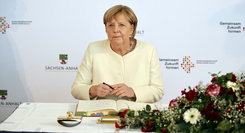Departing German Chancellor Angela Merkel signs Halle city's Golden Book before the a ceremony to mark the 31st anniversary of Germany's reunification on Sunday. Reuters