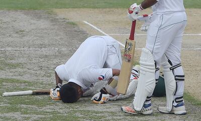Pakistani batsman Babar Azam (L) prostrates as he celebrates scoring a century (100 runs) as captain Sarfraz Ahmed (R) looks on during the second day of the second Test cricket match between Pakistan and New Zealand at the Dubai International Stadium in Dubai on November 25, 2018. / AFP / AAMIR QURESHI
