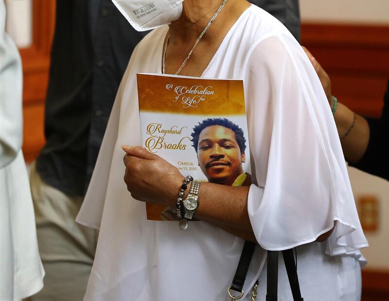 A family member carries the Celebration of Life programme for Rayshard Brooks.  AP