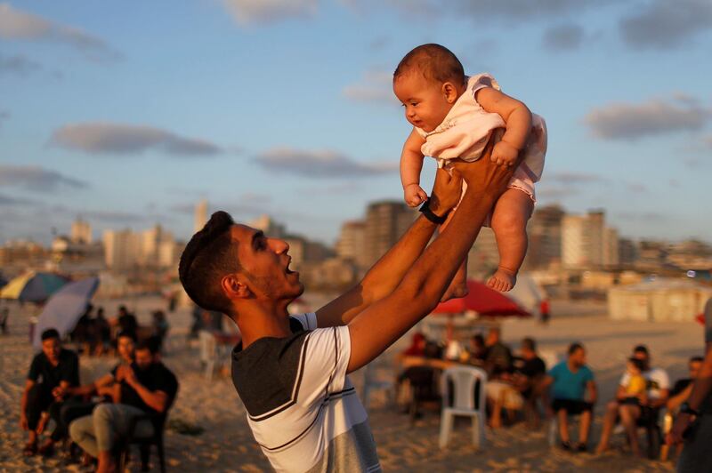 A Palestinian man lifts up a baby on the beach in Gaza City after coronavirus restrictions in the territory were largely eased. Reuters