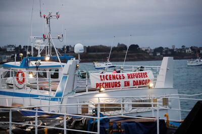 A banner reading "licences refused, fishermen in danger" hangs from a fishing vessel in the port of Saint-Malo. Reuters 