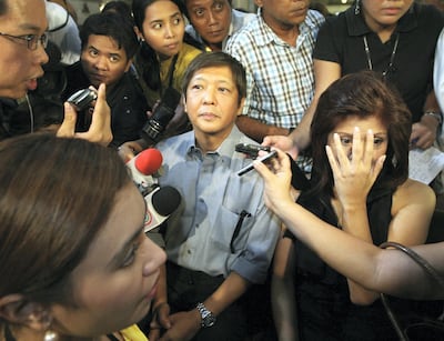 Ferdinand 'Bong-Bong' Marcos Jr. (C) and Imee Marcos (R), the children of the late Philippine president Ferdinand Marcos, are surrounded by reporters after viewing the remains of the late president Corazon Aquino during a visit to Manila Cathedral on August 4, 2009. Drawing on the Roman Catholic Asian nation's long tradition of setting aside rivalries on the occasion of death, House of Representatives member Ferdinand "Bongbong" Marcos Junior and elder sister Imelda "Imee" Marcos surprised mourners with their afternoon visit at the Manila Cathedral wake. Aquino died on August 1 at age 76 after a long battle with cancer.   AFP PHOTO / POOL / ROLEX DELA PENA (Photo by ROLEX DELA PENA / POOL / AFP)