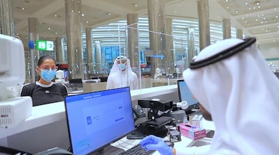 An immigration official checks documents of passenger at Dubai Airport. WAM