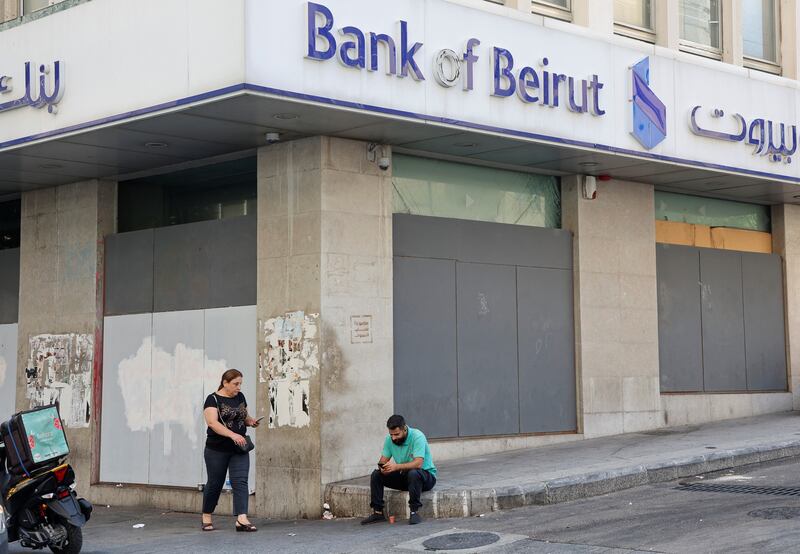 A man sits by a closed Bank of Beirut branch on Tuesday. Reuters