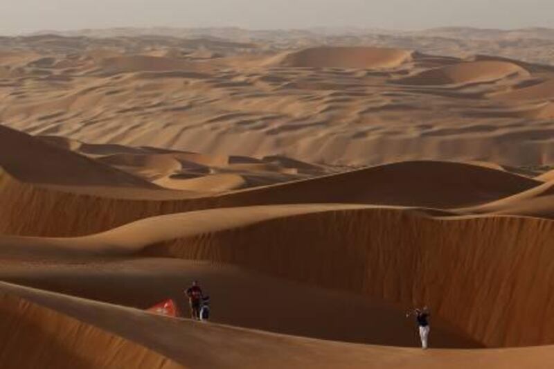 ABU DHABI, UNITED ARAB EMIRATES - JANUARY 24:  Luke Donald of England, the World's Number One golfer, plays from amongst the 250ft high sand dunes in Abu Dhabi's Liwa Desert at the entrance to Rub Al Khali (The Empty Quarter) as his caddie John McLaren looks on as a preview for the 2012 Abu Dhabi HSBC Golf Championship at the Abu Dhabi Golf Club on January 24, 2012 in Abu Dhabi, United Arab Emirates.  (Photo by Andrew Redington/Getty Images) *** Local Caption ***  137681202.jpg