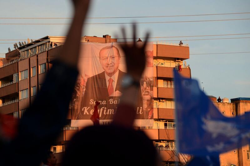 Supporters of the Justice and Development Party (AK Party) wave in front of a portrait of Turkish President Recep Tayyip Erdogan displayed on a building during a local election rally in Diyarbakir, eastern Turkey, on March 9, 2019. Local elections in Turkey's capital and the country's overall 81 provinces are scheduled for March 31, 2019. / AFP / Ilyas AKENGIN

