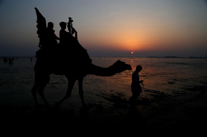 People ride a camel at a beach in Karachi, Pakistan.  EPA