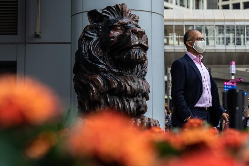A person stands next to a statue of a lion in front of the HSBC Holdings Plc headquarters building in Hong Kong. Bloomberg