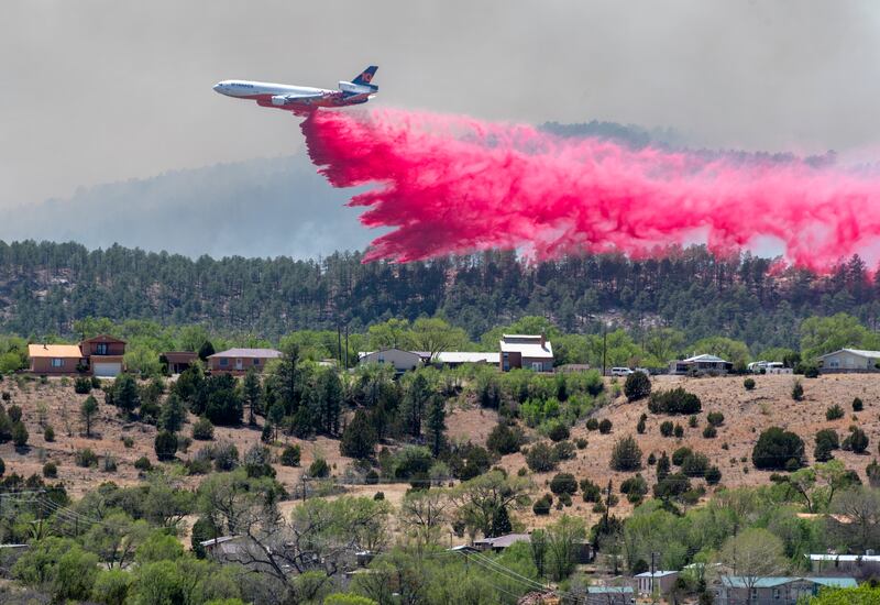 A slurry bomber passes between the Calf Canyon and Hermits Peak fires and homes on the west side of Las Vegas, New Mexico. The Albuquerque Journal / AP