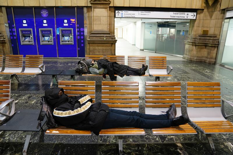 Passengers rest at Edinburgh Waverley train station as rail services to and from Scotland have been suspended. PA