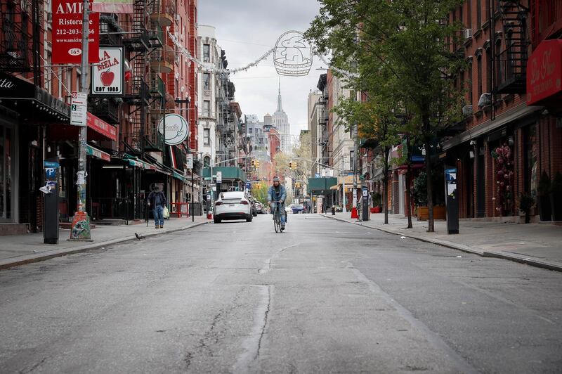 A cyclist rides down an empty Mulberry Street with the Empire State Building looming in the distance as storefronts in the normally bustling tourist district remain closed due to social distancing restrictions, in the Little Italy neighborhood of the Manhattan borough of New York. AP