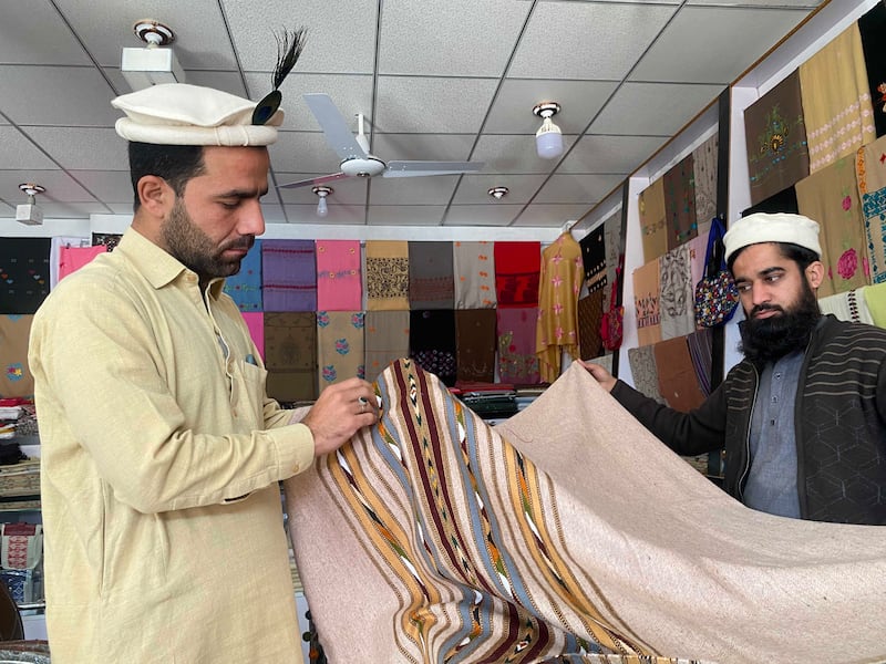 Tourist Mohammad Imran examines a handmade sheep-wool shawl being sold by Bilal, a shop owner in Islampur, Swat valley. All photos: Tariq Ullah for The National