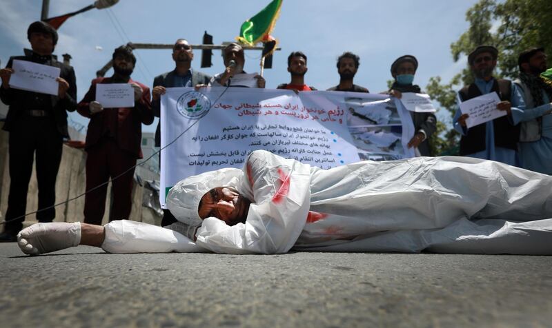 epa08406682 An Afghan man wearing clothes spattered in blood lays down on a road as protesters shout slogans against the Iranian regime and demand justice during a protest outside the Iranian Embassy in Kabul, Afghanistan, 07 May 2020. Dozens of Afghan migrants returned from Iran claim that Iran border guards tortured and killed at least 23 Afghan workers by throwing them into a river on 02 May 2020.  EPA/JAWAD JALALI