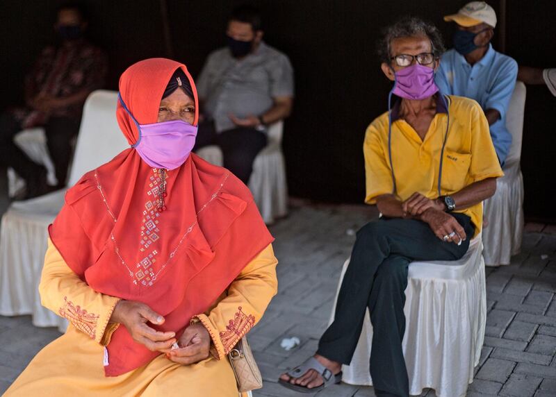 People wear protective masks and sit apart as they wait for the results of their coronavirus antibody tests in North Sumatra, Indonesia. AP