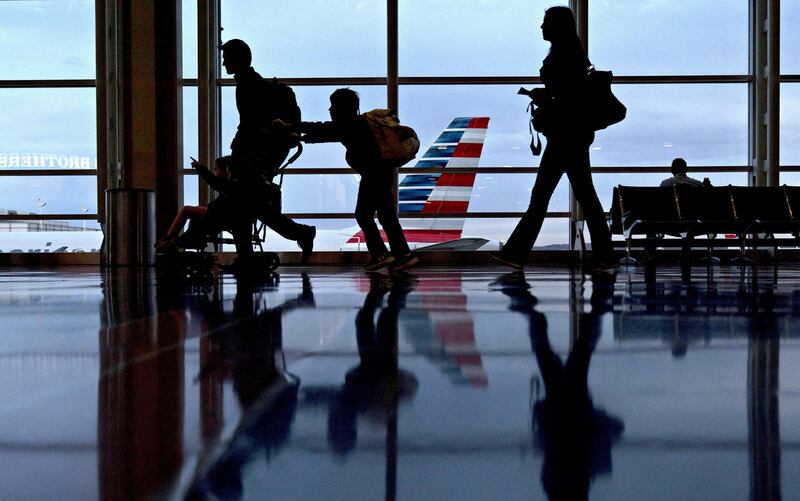 Travelers walk past an American Airlines Group Inc. aircraft at Ronald Reagan National Airport (DCA) in Washington, D.C., U.S., on Wednesday, Nov. 22, 2017. The trade association Airlines for America has projected that 28.5 million passengers will travel on U.S. airlines during the 12-day Thanksgiving air-travel period, up 3 percent from 2016. Photographer: Andrew Harrer/Bloomberg