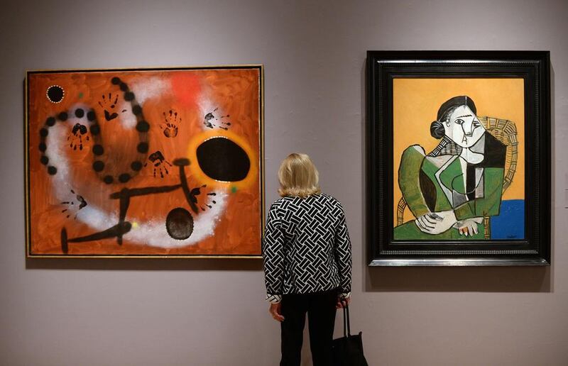 "L'espoir nous revient par la fuite des constellations" by Joan Miro (L) and "Femme assise dans un fauteuil" by Pablo Picasso are on display during a preview of Sotheby's impressionist and modern art evening sale in New York on 2 May, 2014. AFP 