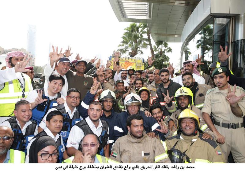 Firefighters and other people involved in the clean up pose with Sheikh Mohammed bin Rashid, Ruler of the emirate and Vice President. WAM