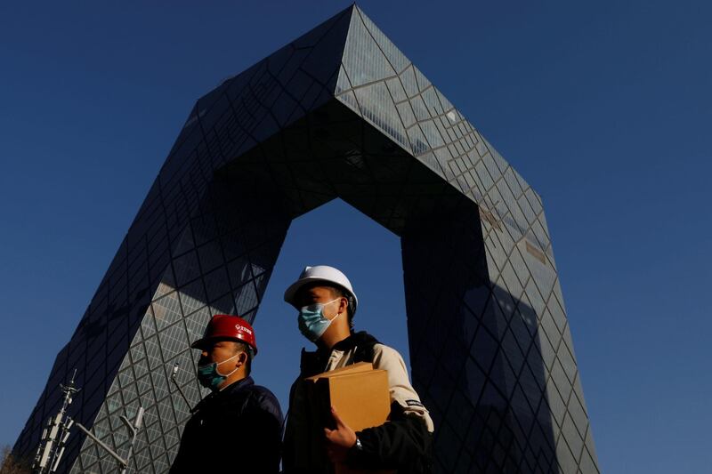 People wearing face masks following the coronavirus disease (COVID-19) outbreak walk past the CCTV headquarters, the home of Chinese state media outlet CCTV and its English-language sister channel CGTN, in Beijing, China February 5, 2021. REUTERS/Carlos Garcia Rawlins