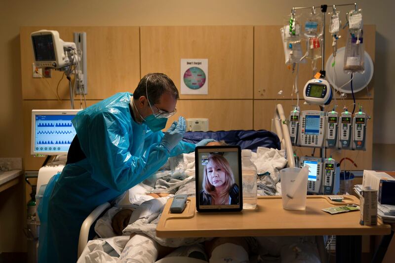Chaplain Kevin Deegan prays for COVID-19 patient Pedro Basulto while on a video call with the patient's daughter, Grace, at Providence Holy Cross Medical Center in the Mission Hills section of Los Angeles. "These video calls have been a lifeline for families," said Deegan. "It can be emotionally exhausting and very draining, but it also an honor to be a bridge for the family." AP Photo