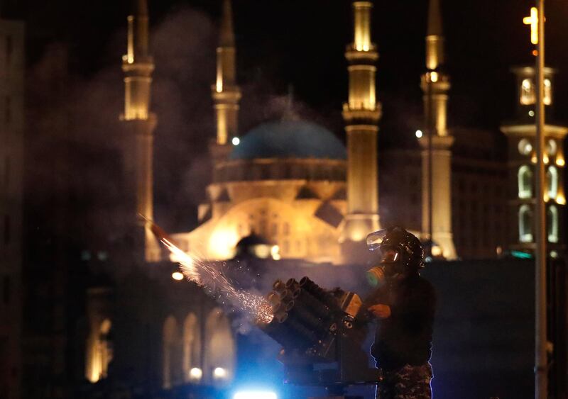 A riot police officer fires tear gas from a launcher against anti-government protesters trying to enter parliament square in downtown Beirut, Lebanon. AP Photo