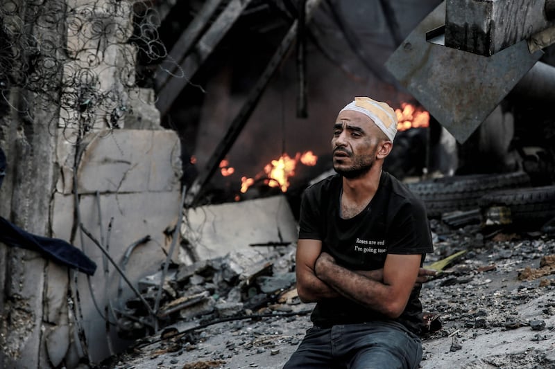 An injured man in front of a smouldering building in the aftermath of an Israeli strike. AFP