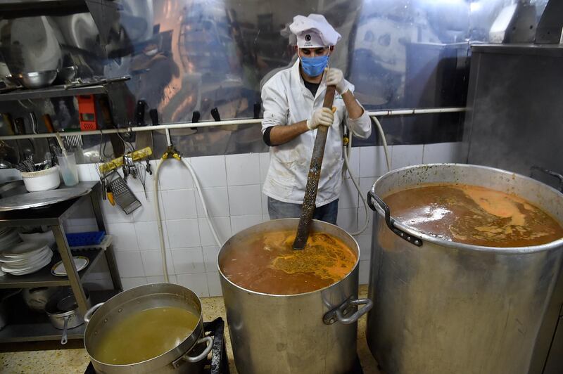 A volunteer of the "Nass el-Khir" association, wearing mask due to the COVID-19 coronavirus pandemic, prepares food for meals to be distributed among those in need during the Muslim holy fasting month of Ramadan, in Algeria's capital Algiers on May 18, 2020. (Photo by RYAD KRAMDI / AFP)