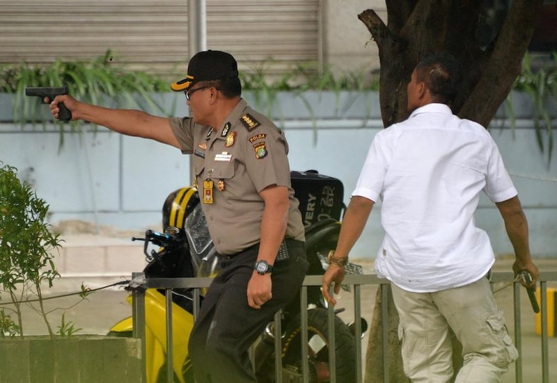 An Indonesian policeman fires his handgun towards suspects outside a cafe. Bay Ismoyo / AFP Photo