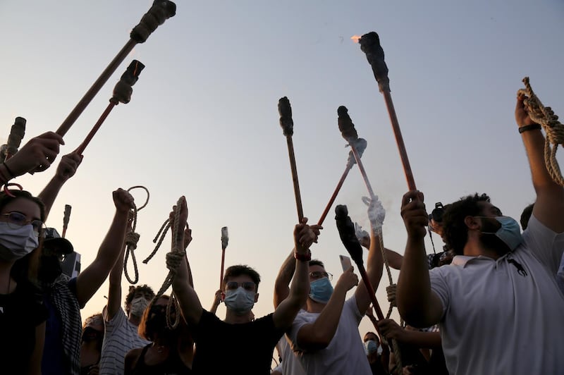 Protesters carry torches and hangman noose as they demand the punishment of those responsible for the port explosion during a moment of silence to mark one month of Beirut port explosion. EPA