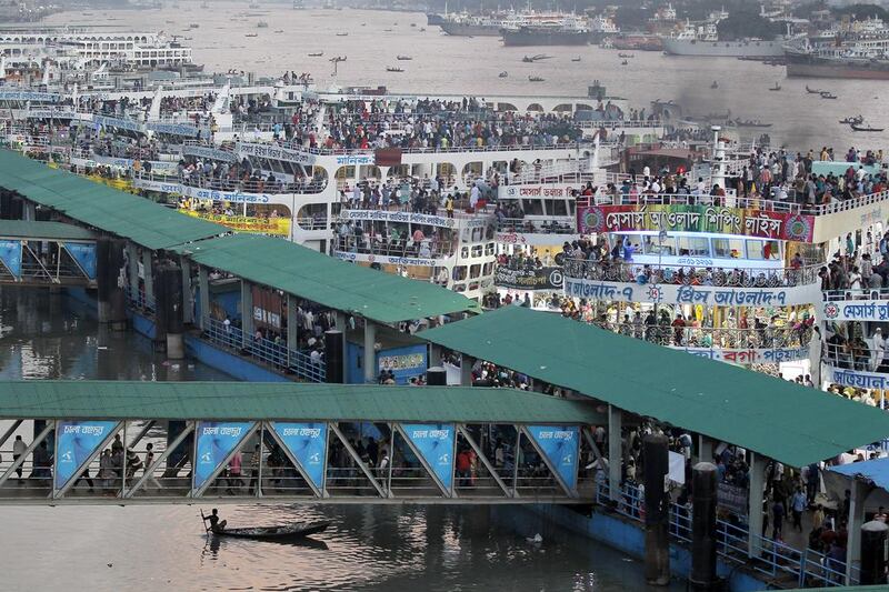 A boy rows a boat, bottom left, past a ferry terminal crowded with people traveling to their hometowns for Eid Al Adha festival in Dhaka, Bangladesh. A M Ahad / AP Photo