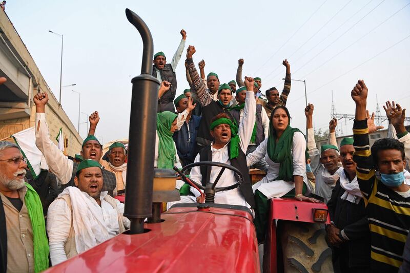 Farmers on a tractor trolley shout slogans near a police road block stopping them from marching to New Delhi to protest against the central government's recent agricultural reforms at the Delhi-Uttar Pradesh state border in Ghazipur on December 1, 2020.  / AFP / Sajjad HUSSAIN
