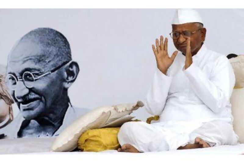 Indian activist Anna Hazare, 73, gestures during his hunger strike against corruption, besides a portrait of Mahatma Gandhi, in New Delhi