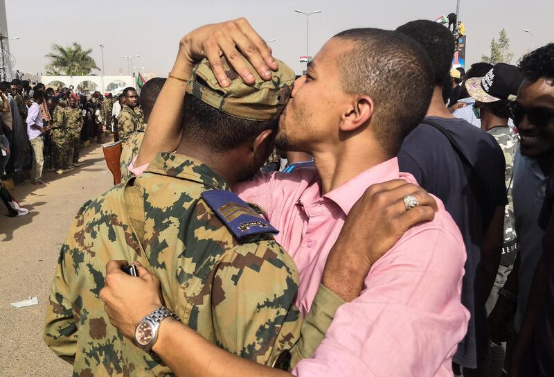 A Sudanese anti-regime protester kisses a soldier on the head during protests on April 11, 2019 in the area around the army headquarters in Sudan's capital Khartoum. - The Sudanese army is planning to make "an important announcement", state media said today, after months of protests demanding the resignation of longtime leader President Omar al-Bashir. Thousands of Khartoum residents chanted "the regime has fallen" as they flooded the area around the military headquarters, where protesters have held an unprecedented sit-in now in its sixth day. (Photo by - / AFP)