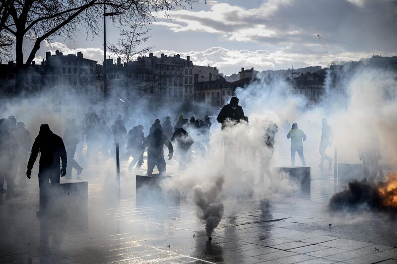 Protesters try to protect themselves from tear gas during an anti-government demonstration called by the Yellow Vests (gilets jaunes) movement in Lyon, central-eastern France, on March 2, 2019. / AFP / JEAN-PHILIPPE KSIAZEK
