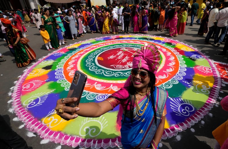 A woman takes a selfie against a rangoli in the background to mark Gudi Padwa. AP