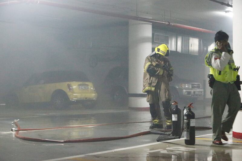 DUBAI, UNITED ARAB EMIRATES,  JUNE 18, 2013. Civil Defense clear up their equipment after extinguishing a yellow Mini Cooper car that caught fire in the basement level of the Shatha Tower, Media City.  (ANTONIE ROBERTSON / The National) *** Local Caption ***  AR_1806_Shatha_Tower_Car_Fire08.jpg