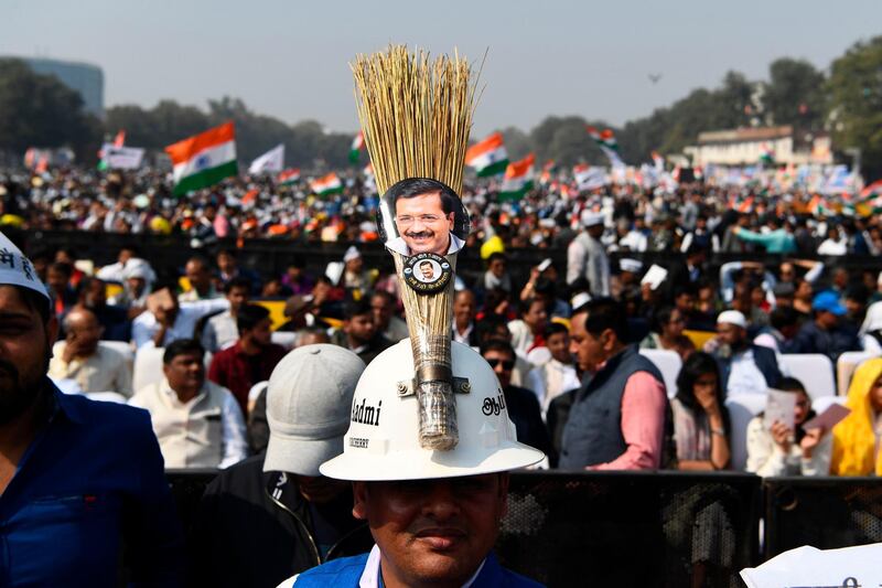 A supporter of the Aadmi Party (AAP) wearing a helmet decorated with the party's symbol and a picture of Arvind Kejriwal looks on after Kejriwal's swearing-in ceremony as Delhi Chief Minister, in New Delhi.  AFP