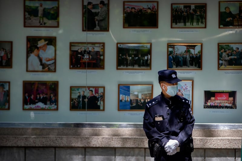 A Chinese policeman wears a face mask as he stands in front of a display of photos of North Korean leaders outside the North Korean embassy in Beijing, Tuesday, April 21, 2020. AP Photo