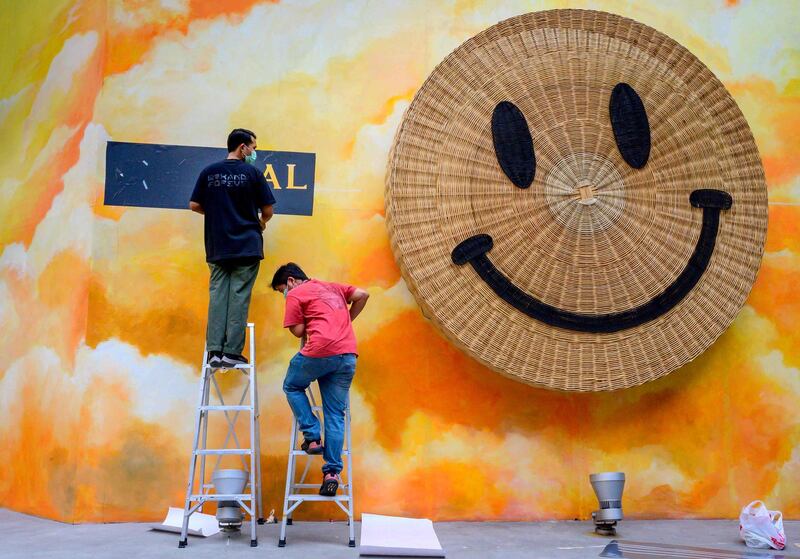 A sign is hung next to a rotating smiley face outside a shopping mall in Bangkok, Thailand. AFP Antonov