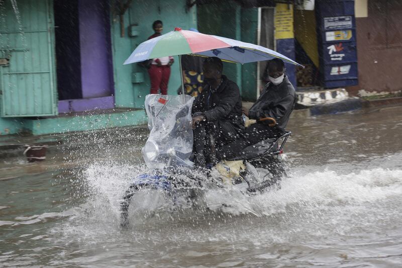 A motorcycle taxi rides through a flooded street in Liberia, with many developing countries especially vulnerable to extreme weather caused by climate change. EPA