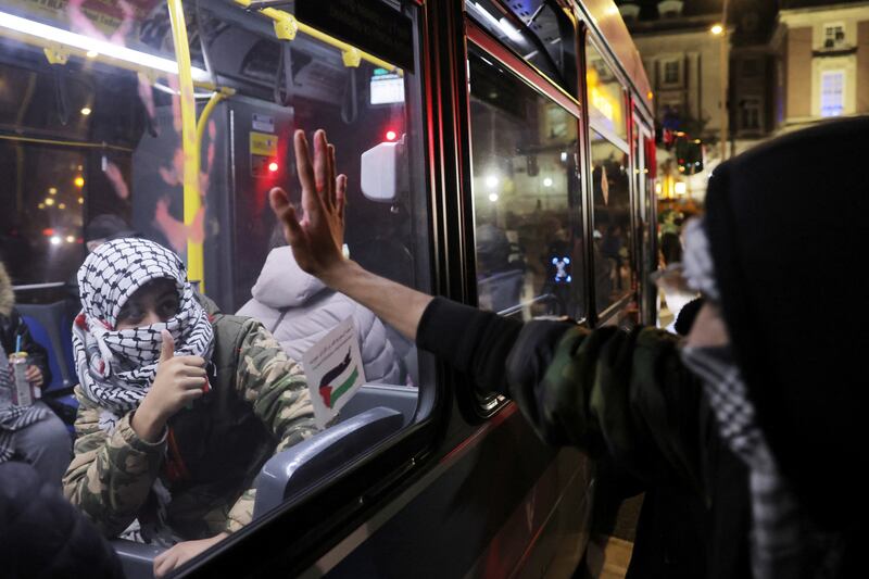 A bus passenger wearing a keffiyeh gestures to a protester also wearing one on Staten Island, New York, on November 14, 2023. Reuters