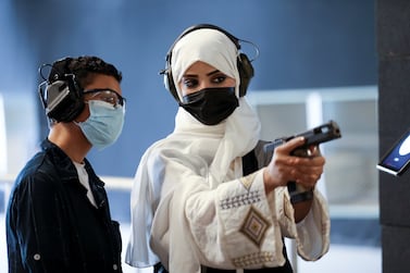 Saudi female firearm trainer, Mona Al Khurais, teaches a Saudi boy on safe usage of weapons at the Top-Gun shooting range in Riyadh, Saudi Arabia, October 28, 2021. Picture taken October 28, 2021. REUTERS/Ahmed Yosri